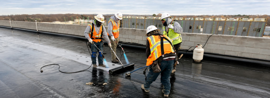 Alliance One roofing crew torching a flat roof membrane on site